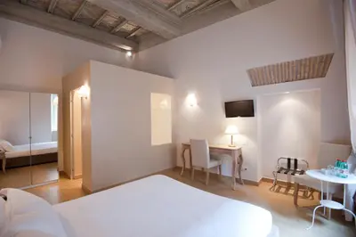 a bedroom with a bed and a desk and a table at Little Queen Suite in Rome