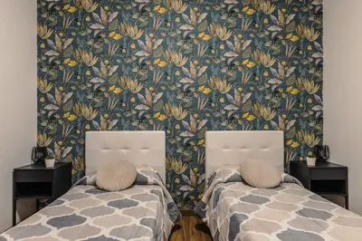 two beds in a room with a floral wallpaper at Nvmen Apartment con Terrazza al Colosseo in Rome