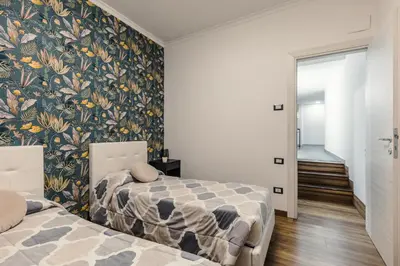 a bedroom with two beds and a floral wallpaper at Nvmen Apartment con Terrazza al Colosseo in Rome