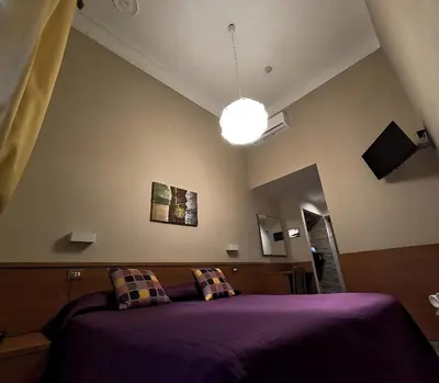 a bedroom with a purple bed and a light at Hotel Cervia in Rome