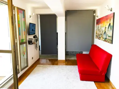 a red chair in a living room with a window at Appartamento con magnifico terrazzo vicino a Metropolitana e Vaticano in Rome