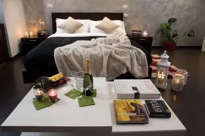 a bed with a table with a bottle of wine and a book at Chroma Italy - Chroma Pente in Rome
