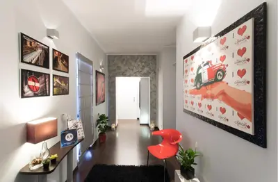 a hallway with a red chair and a painting on the wall at Chroma Italy - Chroma Pente in Rome