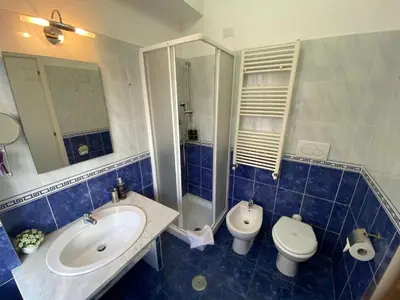a blue tiled bathroom with a sink and a toilet at Domus Prati in Rome