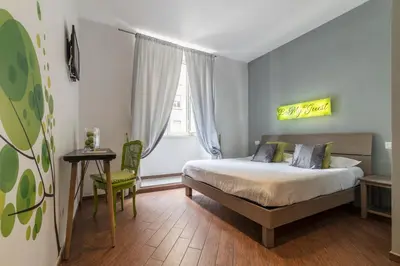 a bedroom with a bed and a chair and a window at Be My Guest in Rome