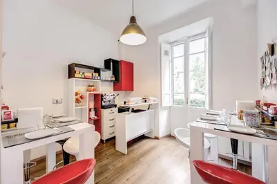 a kitchen with white counters and red chairs at Imperia Suite in Rome