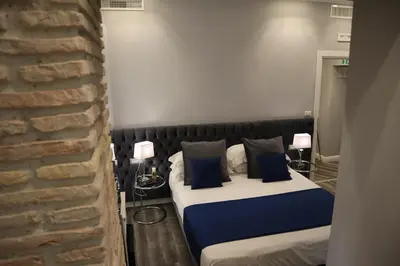 a bedroom with two beds with blue pillows and a brick wall at MILLINA SUITES IN NAVONA in Rome