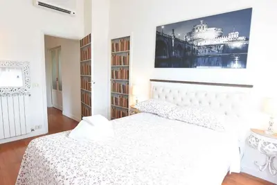 a white bedroom with a white bed and bookshelves at Romantic Flat near Metro Flaminio in Rome