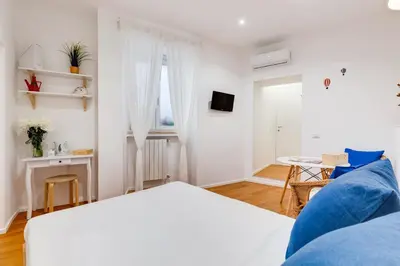 a white bedroom with a bed and a table at Lovely and modern nest near the Colosseum in Rome