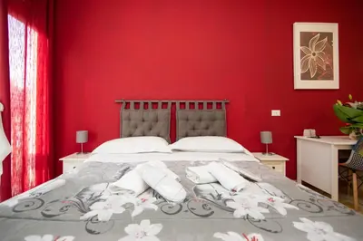 a bedroom with red walls and a bed with two pillows at L'Imperiale RomaTrastevere in Rome