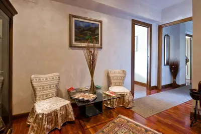 a living room with two chairs and a table with a vase at B&B Roma Appia Davila25 in Rome