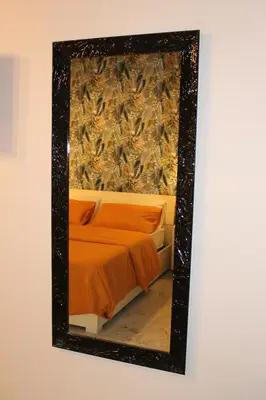 a mirror hanging on a wall next to a bed at Guest House Esty in Rome