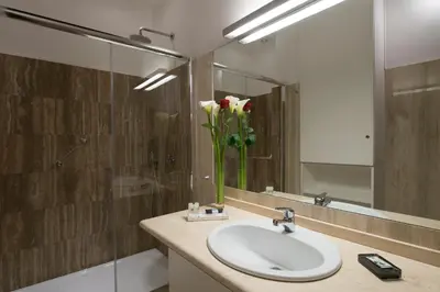 a bathroom with a sink and a vase of flowers at JR Suites in Rome