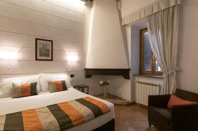 a bedroom with a bed and a chair and a window at JR Suites in Rome