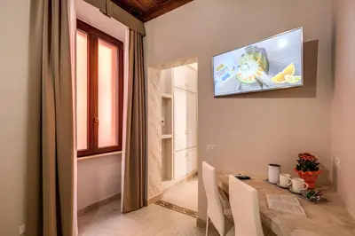 a dining room with a table and a television on the wall at Colosseo Accomodation Room Guest House in Rome