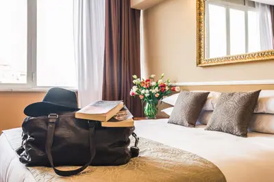 a hotel room with a backpack and a chair on a bed at Raeli Hotel Lux in Rome