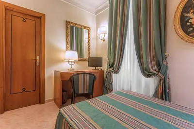 a bedroom with a bed and a desk and a chair at Raeli Hotel Luce in Rome