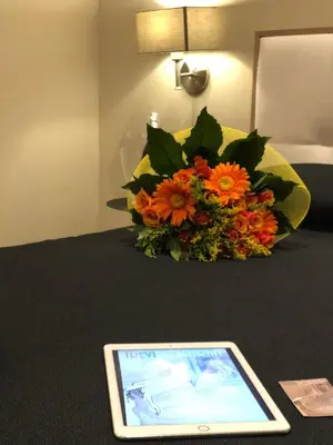 a tablet on a bed with a bouquet of flowers at Trevi Portrait in Rome