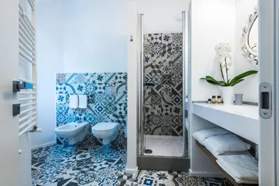 a bathroom with a toilet and a shower with blue and white tiles at Giselda Home in Rome