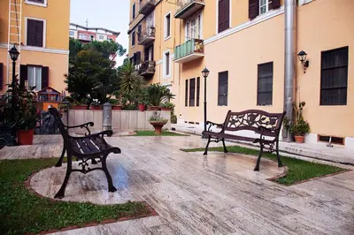 two benches sitting in a courtyard next to buildings at Paola Guest House in Rome
