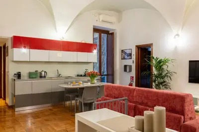 a kitchen and a living room with a red couch at ROMAC Coronari with gym, sauna and garden in Rome