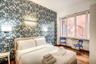 a bedroom with a bed and blue floral wallpaper at Holiday Apartment Bernini Near The Trevi Fountain - 4 Bedroom in Rome