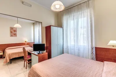 a bedroom with two beds and a table with a television at Hotel Katty in Rome