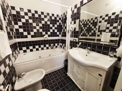 a bathroom with black and white checkered walls and a tub and sink at Colosseo Rooms Imperial Rome in Rome
