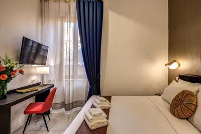a bedroom with a bed and a desk and a window at Little Queen Pantheon in Rome