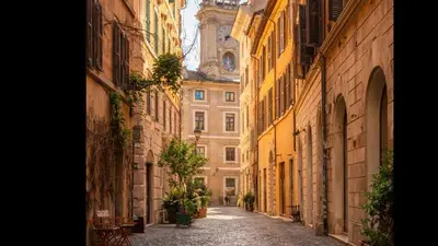 an empty alley with a clock tower in the background at NAVONA & CASTEL SANT'ANGELO WHOLE HOLIDAY APARTMENT da PAMINO & PRISCILLA in Rome
