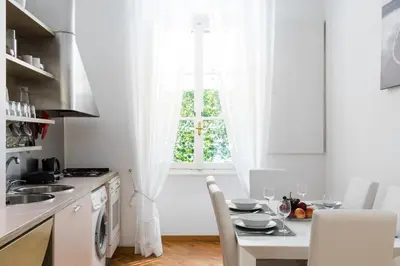 a white kitchen with a table and a window at A World Aparts - 32 Calabria in Rome
