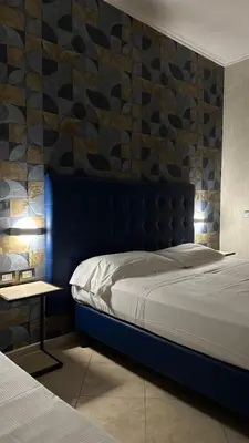a bedroom with a bed with a blue headboard and a table at San Paolo Guest House in Rome