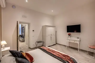 a bedroom with a bed and a desk and a television at Vatican Royal Apartment in Rome