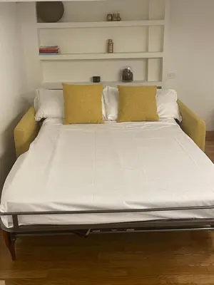 a large bed with white sheets and yellow pillows at House Domusella in Rome
