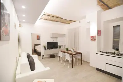 a white living room with a table and a kitchen at LATERANO 250 - COLOSSEO in Rome