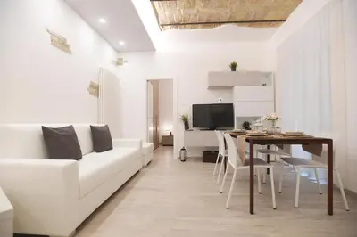 a living room with a white couch and a table at LATERANO 250 - COLOSSEO in Rome