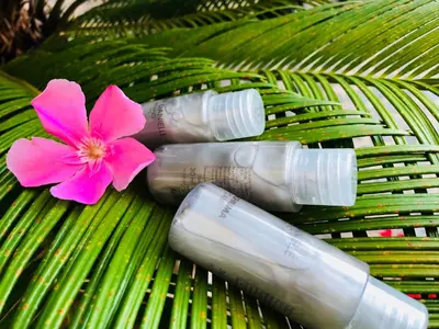 three glass bottles with a pink flower on a green leaf at S.Apollonia Suite Trastevere in Rome