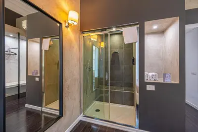 a bathroom with a shower and a mirror and a bed at Four Rivers Suites in Rome
