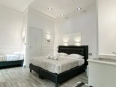a white bedroom with a black bed with white pillows at Locanda Parlamento in Rome