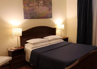 a bedroom with a bed with two lamps and a painting at The Center Of Rome B&B in Rome