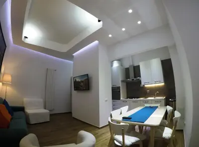 a kitchen and a living room with a table and chairs at Poliziano Apartment in Rome