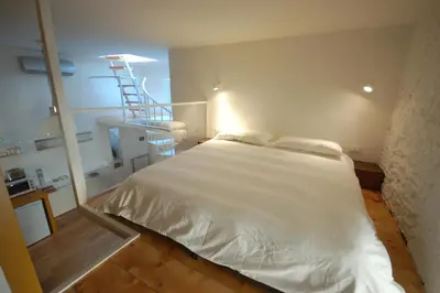 a bedroom with a white bed and a staircase at LOST&FOUND in Trastevere in Rome
