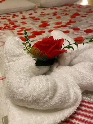 a white towel with a red rose on a table at VaticanSky rooms in Rome