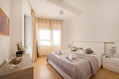a white bedroom with a large bed and a table at World Wide Bed San Giovanni in Rome