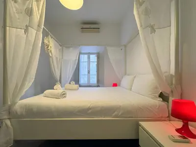 a bedroom with a white bed with curtains and a window at JHHIT San Pietro Modern Suite in Rome