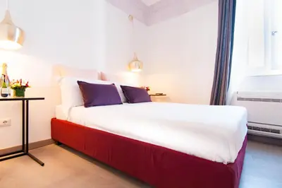 a bedroom with a large white bed with purple pillows at Margana Tower in Rome