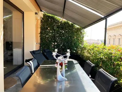 a table and chairs on a patio with a green wall at Casa Terrazza Colosseo in Rome