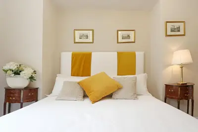 a bedroom with a white bed with yellow pillows at Daplace - Gaia Apartment in Rome