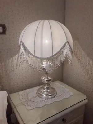 a silver lamp with a white lampshade on a table at The Queen's Coffer Rome in Rome