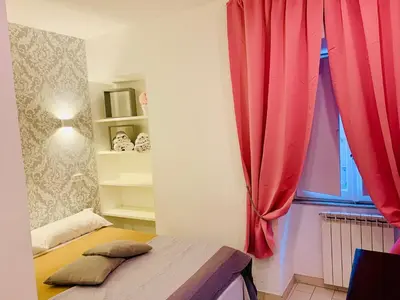 a bedroom with a bed and a window with red curtains at Chroma Apt Farinone 28 in Rome